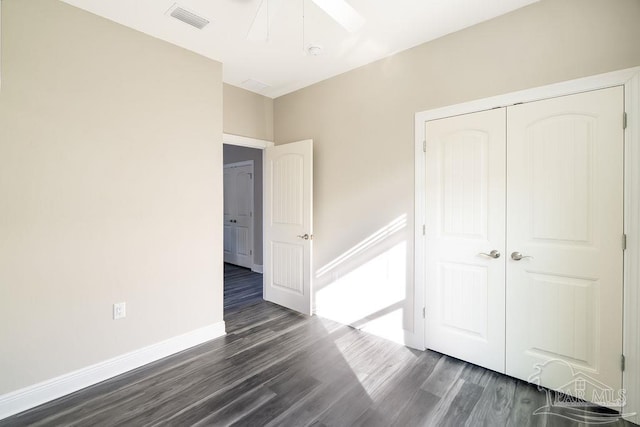 unfurnished bedroom with ceiling fan, dark wood-type flooring, and a closet