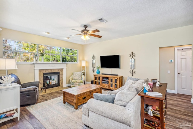 living room featuring a textured ceiling, dark hardwood / wood-style floors, ceiling fan, and a fireplace