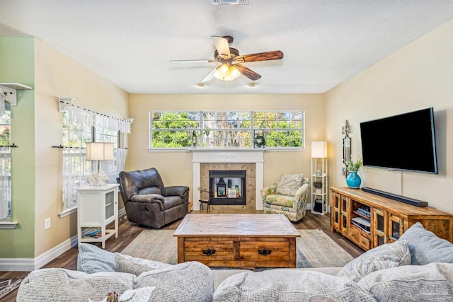 living room with a fireplace, ceiling fan, plenty of natural light, and wood-type flooring