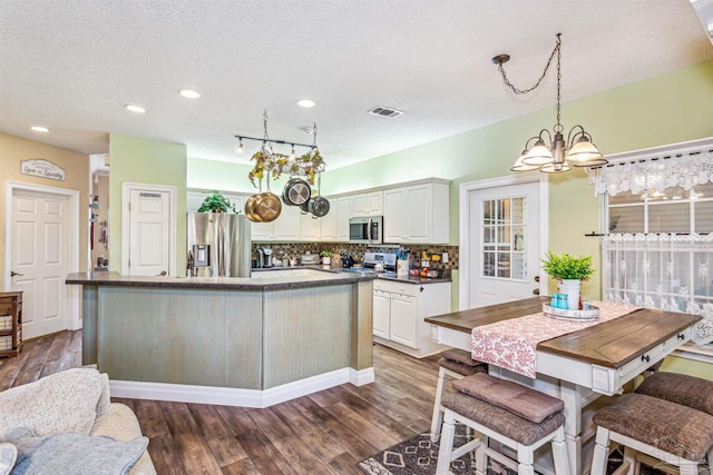 kitchen featuring dark hardwood / wood-style flooring, tasteful backsplash, a textured ceiling, stainless steel appliances, and white cabinets