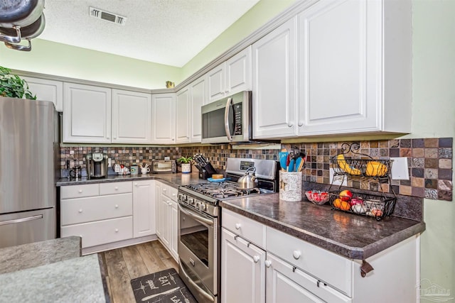 kitchen featuring white cabinets, light hardwood / wood-style floors, stainless steel appliances, and a textured ceiling