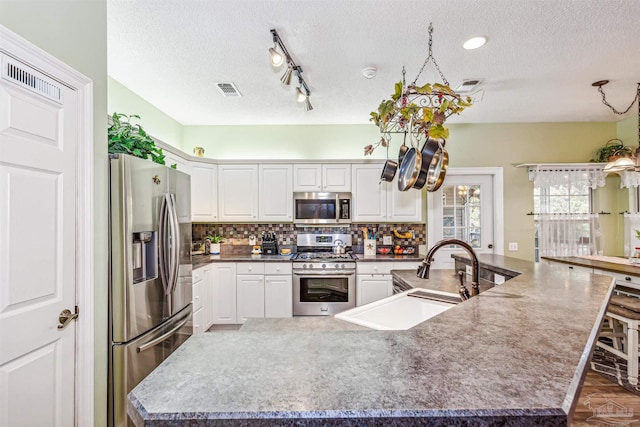 kitchen featuring sink, a large island with sink, a kitchen bar, white cabinets, and appliances with stainless steel finishes