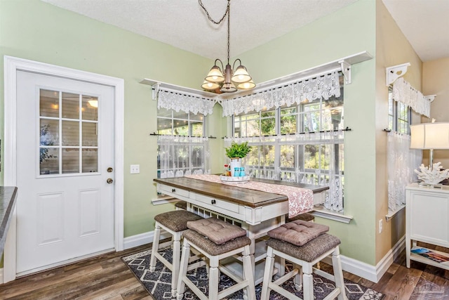 dining room with plenty of natural light, dark wood-type flooring, and an inviting chandelier