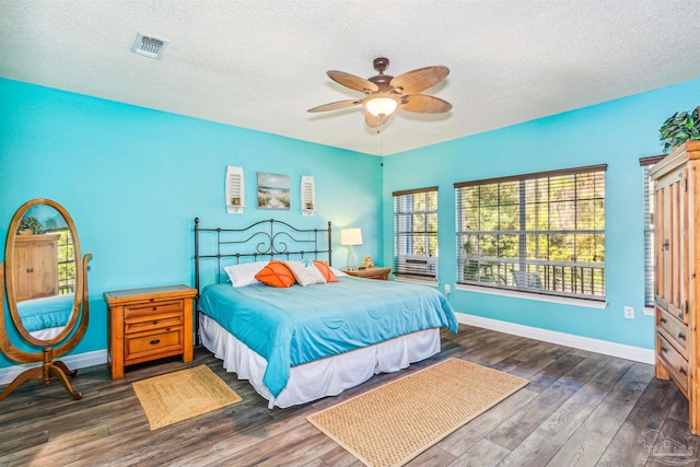 bedroom with a textured ceiling, ceiling fan, and dark wood-type flooring