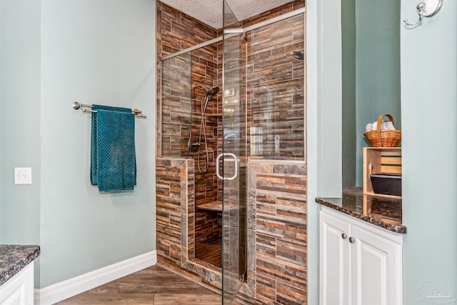 bathroom with a shower with door, vanity, wood-type flooring, and a textured ceiling