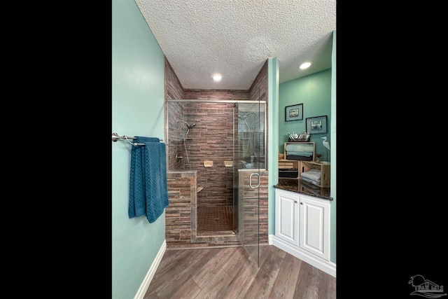 bathroom featuring wood-type flooring, a textured ceiling, and a shower with door