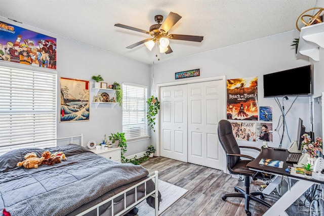 bedroom featuring a closet, ceiling fan, light hardwood / wood-style flooring, and a textured ceiling