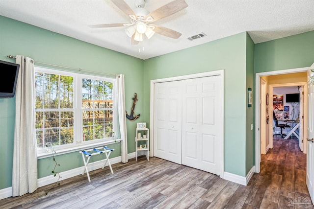 unfurnished bedroom with hardwood / wood-style floors, ceiling fan, a textured ceiling, and a closet