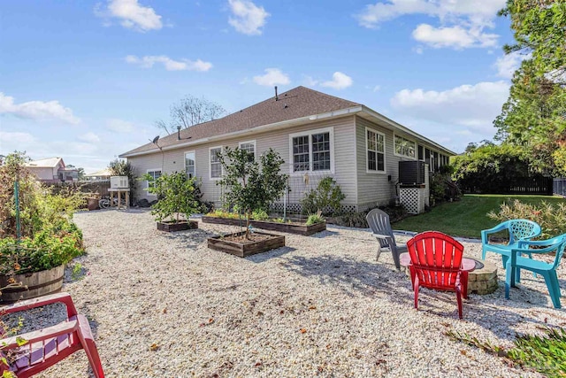 rear view of property featuring an outdoor fire pit and a lawn