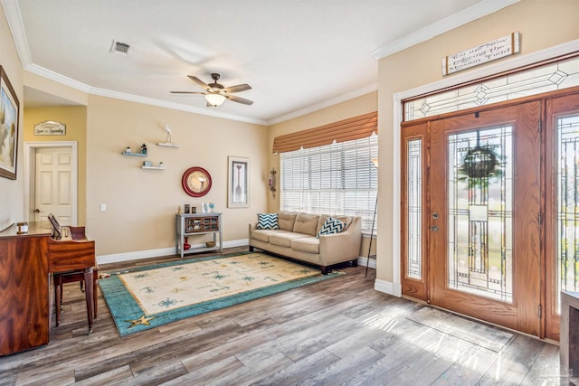 entrance foyer with a healthy amount of sunlight, ceiling fan, wood-type flooring, and ornamental molding