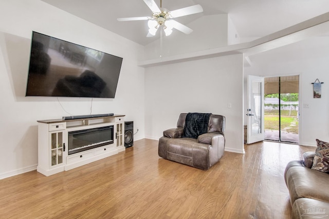living room with baseboards, high vaulted ceiling, ceiling fan, and light wood-style floors