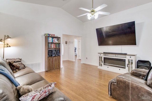 living room with high vaulted ceiling, a ceiling fan, visible vents, light wood-style flooring, and baseboards