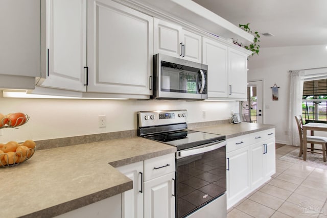 kitchen with light tile patterned flooring, white cabinets, appliances with stainless steel finishes, and light countertops