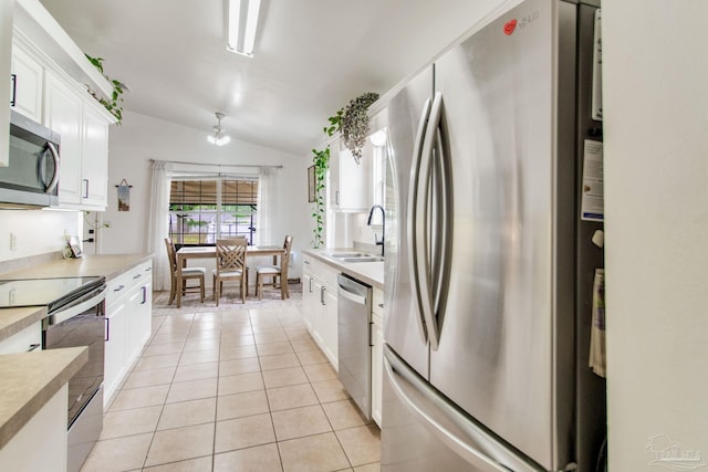 kitchen featuring a sink, stainless steel appliances, white cabinetry, vaulted ceiling, and light countertops
