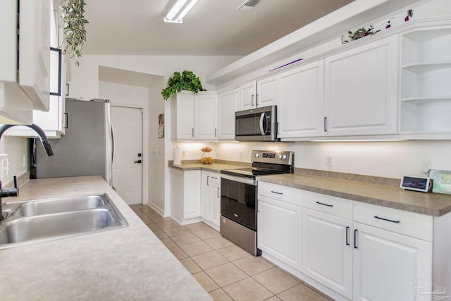 kitchen with lofted ceiling, a sink, white cabinets, and stainless steel appliances