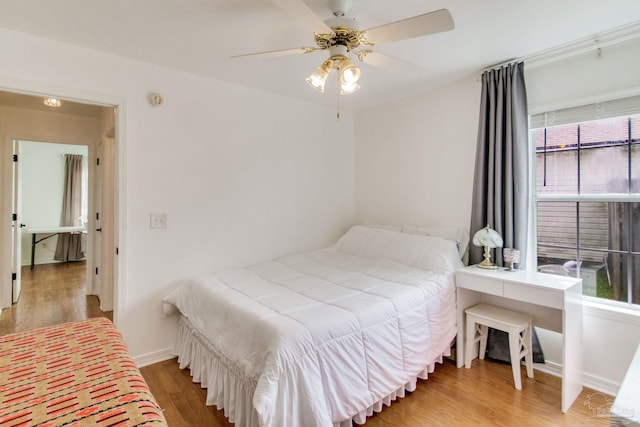 bedroom featuring baseboards, wood finished floors, and multiple windows
