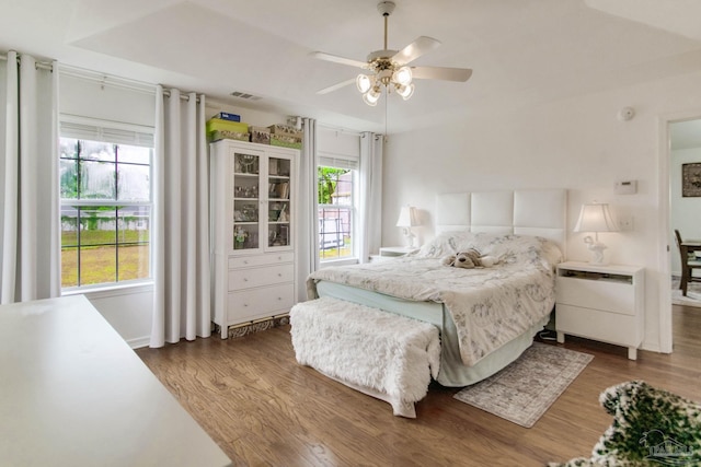 bedroom with visible vents, multiple windows, and wood finished floors