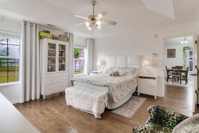 bedroom with a ceiling fan, visible vents, and wood finished floors