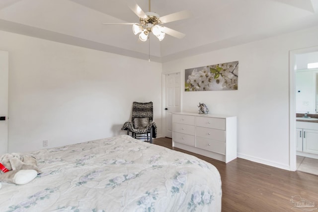 bedroom with dark wood-style floors, a sink, a ceiling fan, baseboards, and ensuite bathroom