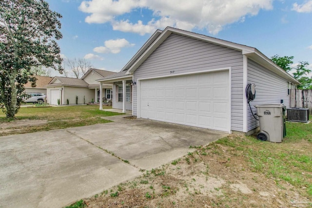 ranch-style house with a front yard, concrete driveway, central AC, and an attached garage