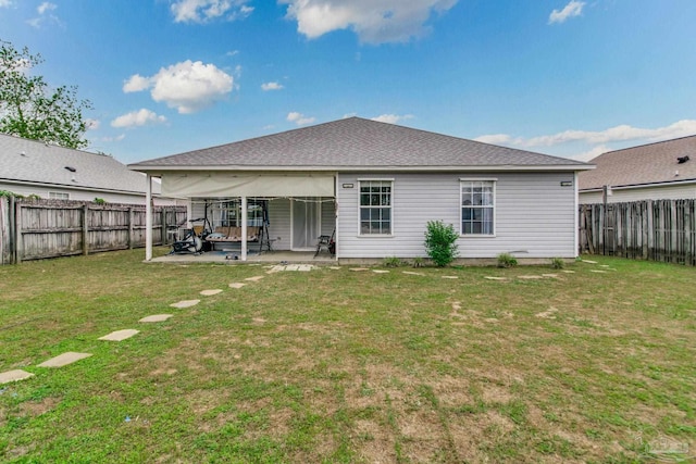 back of house featuring roof with shingles, a patio area, a yard, and a fenced backyard