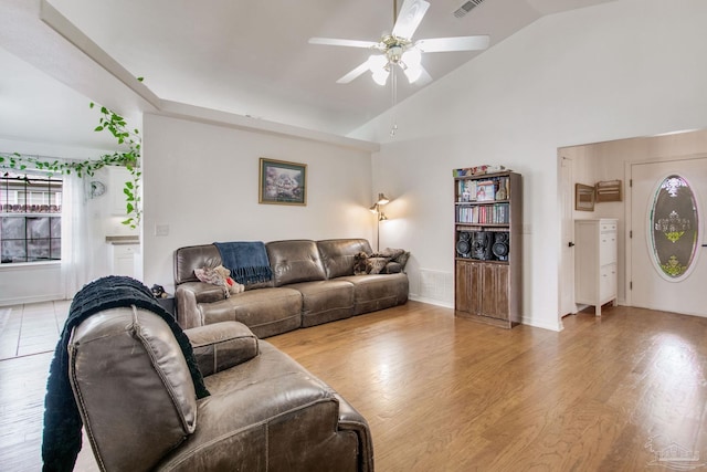 living area with visible vents, a ceiling fan, light wood finished floors, and high vaulted ceiling