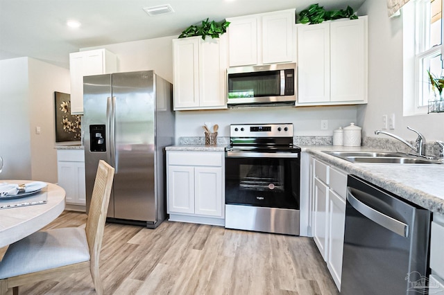 kitchen featuring white cabinets, sink, stainless steel appliances, and light hardwood / wood-style flooring