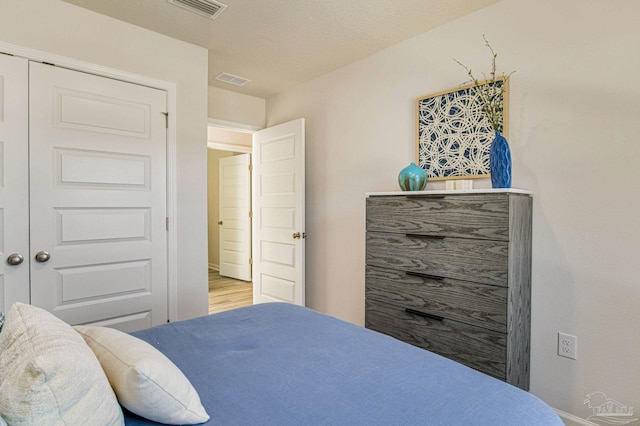 bedroom with a textured ceiling, light hardwood / wood-style floors, and a closet