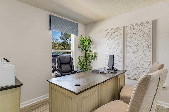 office area with light wood-type flooring and a textured ceiling