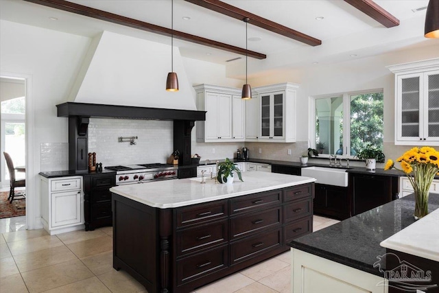 kitchen with tasteful backsplash, a healthy amount of sunlight, sink, beamed ceiling, and a kitchen island