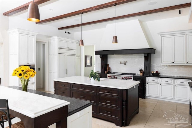 kitchen featuring decorative backsplash, beam ceiling, light tile patterned floors, decorative light fixtures, and a kitchen island