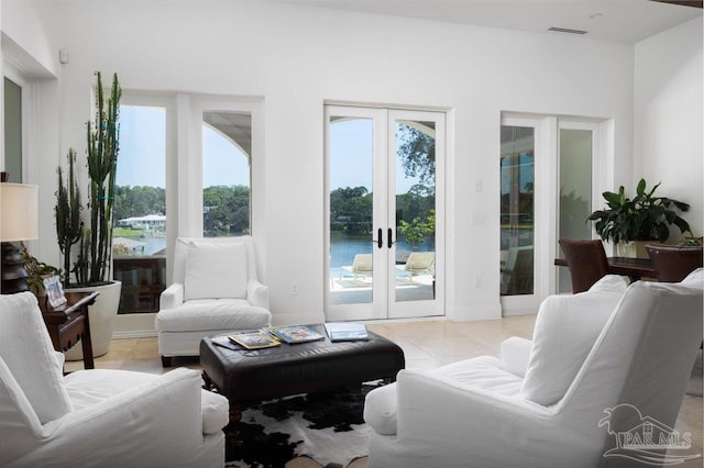 tiled living room featuring a water view and french doors