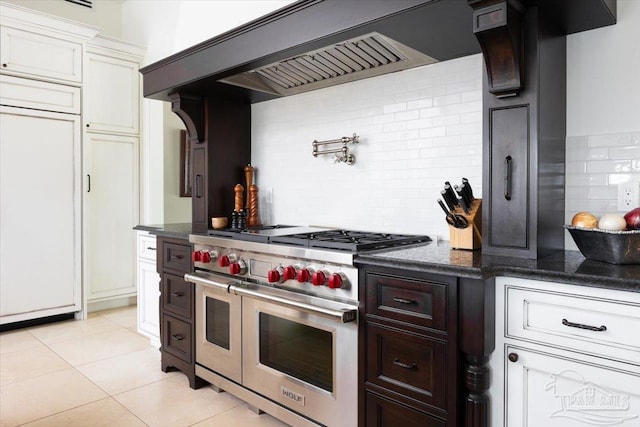 kitchen with premium appliances, tasteful backsplash, light tile patterned flooring, premium range hood, and white cabinets