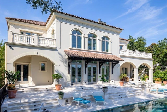 back of property featuring a patio area, a balcony, and french doors