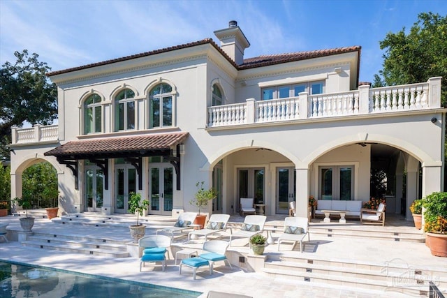 back of property featuring an outdoor living space, french doors, ceiling fan, a balcony, and a patio