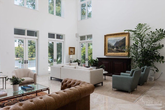 living room with a water view, a high ceiling, and french doors