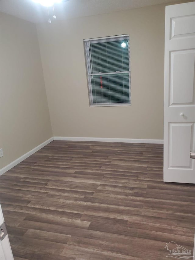 spare room with dark wood-style floors and baseboards