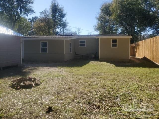 rear view of property with fence and a yard