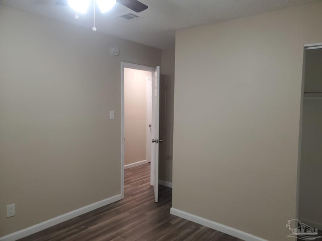 spare room featuring dark wood-style floors, visible vents, ceiling fan, and baseboards