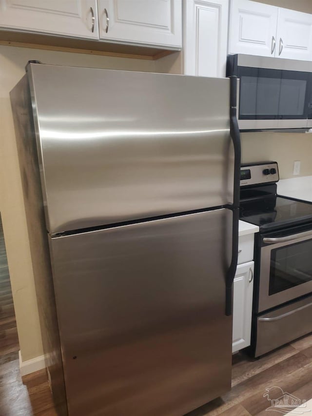 kitchen with baseboards, white cabinetry, stainless steel appliances, and dark wood-type flooring