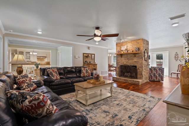 living room featuring a fireplace, crown molding, dark wood-type flooring, and a textured ceiling