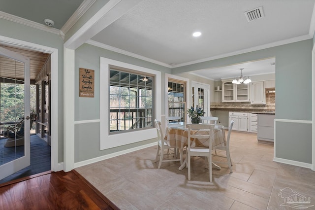 dining space with french doors, ornamental molding, and a chandelier