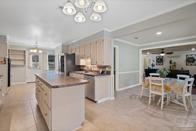 kitchen featuring appliances with stainless steel finishes, decorative light fixtures, sink, a center island, and crown molding