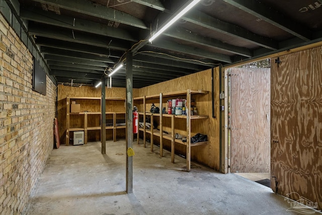 basement featuring brick wall and electric panel