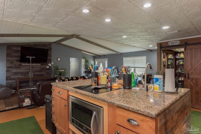 2322 Silversides Loop, Pensacola, FL 32526 - kitchen with stainless steel microwave, vaulted ceiling, black electric cooktop, a barn door, and a center island