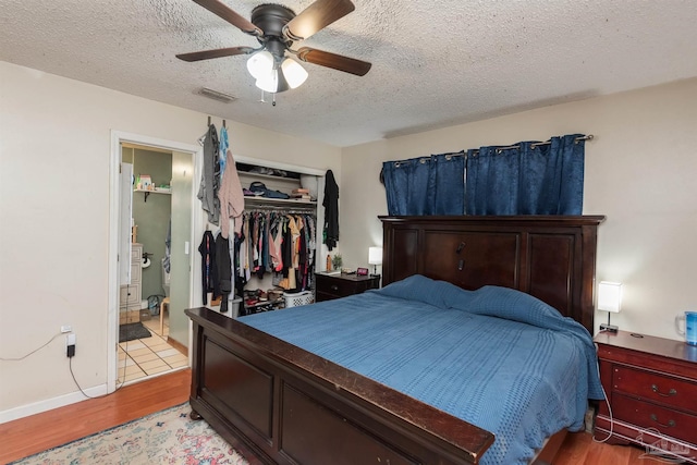 2322 Silversides Loop, Pensacola, FL 32526 - bedroom with light wood finished floors, a textured ceiling, a closet, a ceiling fan, and ensuite bath