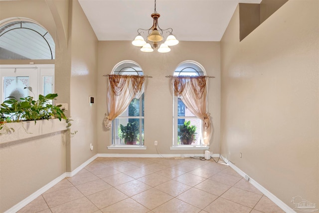 tiled spare room with a chandelier