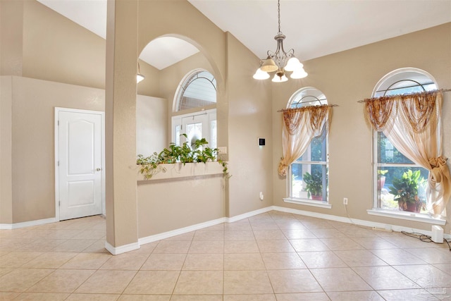 tiled entrance foyer with lofted ceiling and a chandelier