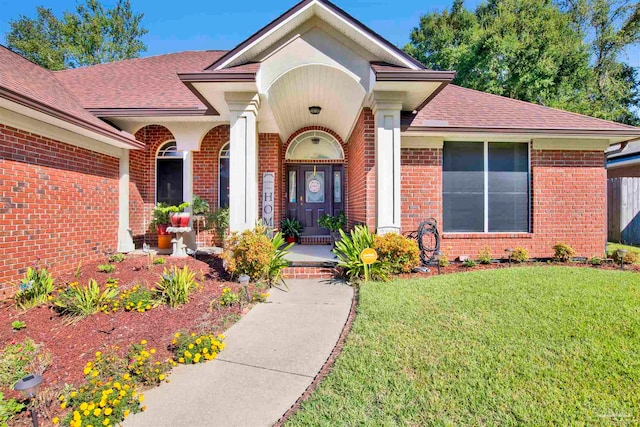 view of exterior entry featuring a lawn