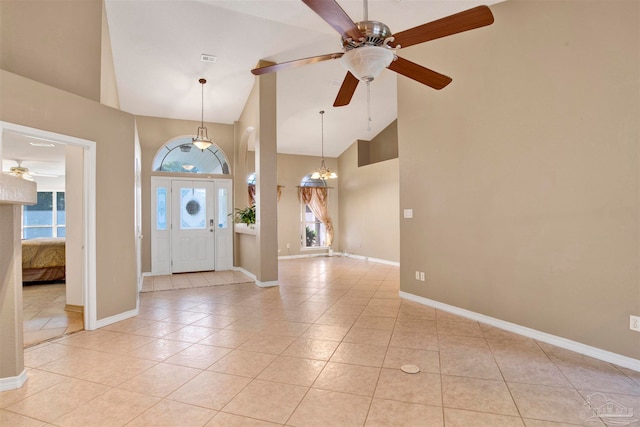 tiled foyer featuring high vaulted ceiling, plenty of natural light, and ceiling fan with notable chandelier